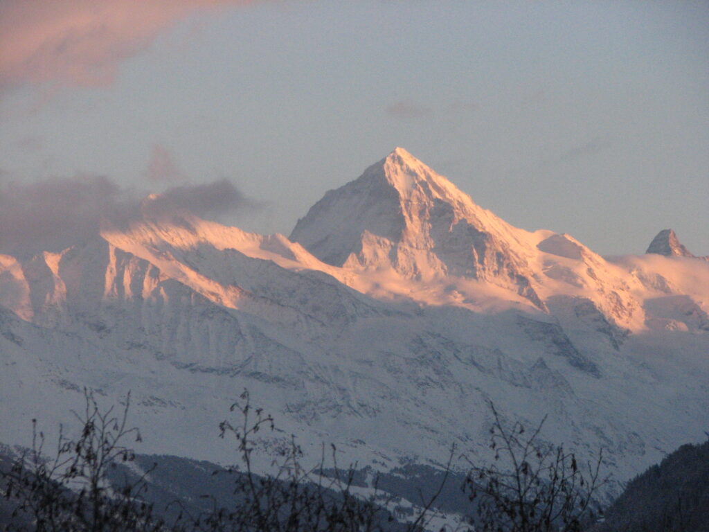 Regardez le soleil couchant briller à travers les sommets des montagnes