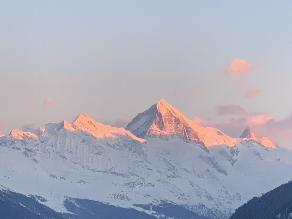 Zie de ondergaande zon door de bergtoppen schijnen